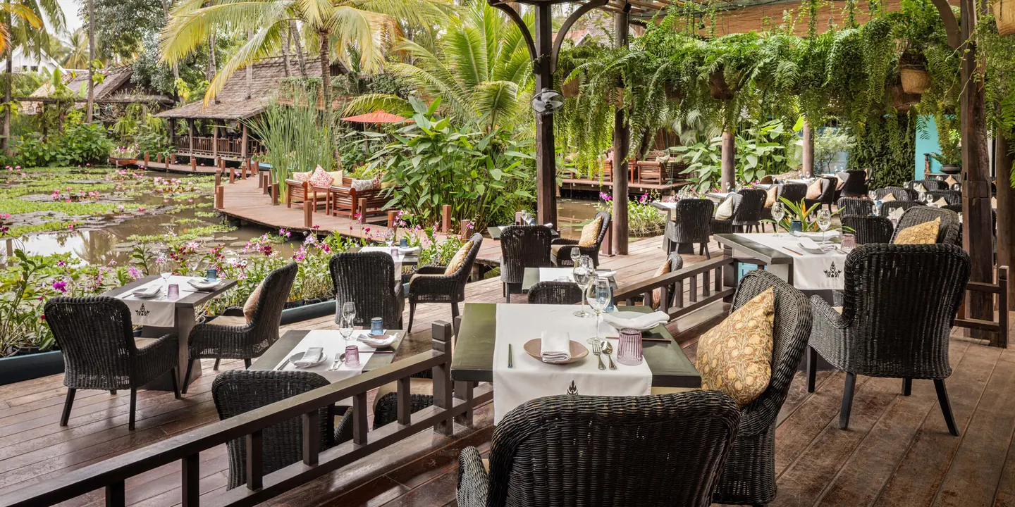 Pond-side terrace dining at Manda de Laos, tables set beside the lily ponds